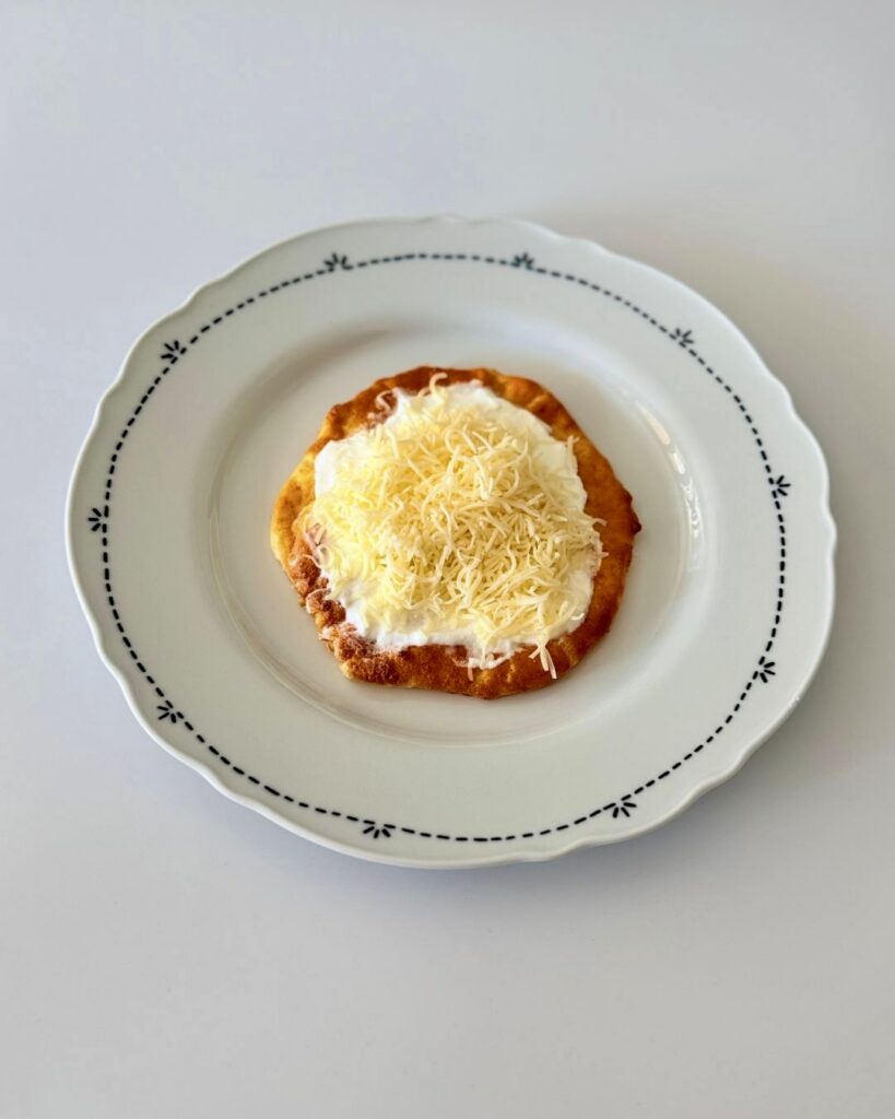 Sütőben sült felhőlángos tejföllel, reszelt sajttal és lilahagymával megpakolva, egészségesebb lángos alternatívaként tálalva.