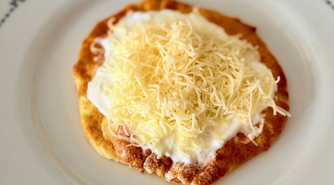Sütőben sült felhőlángos tejföllel, reszelt sajttal és lilahagymával megpakolva, egészségesebb lángos alternatívaként tálalva.