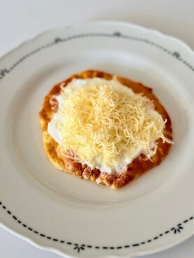 Sütőben sült felhőlángos tejföllel, reszelt sajttal és lilahagymával megpakolva, egészségesebb lángos alternatívaként tálalva.