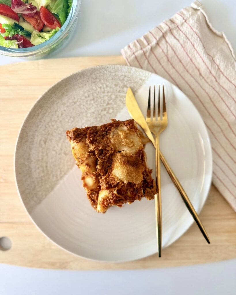 Házi marharagus lasagne olvadt mozzarellával rétegezve, szeletelve, paradicsomos szósszal és zöldséges raguval készítve.