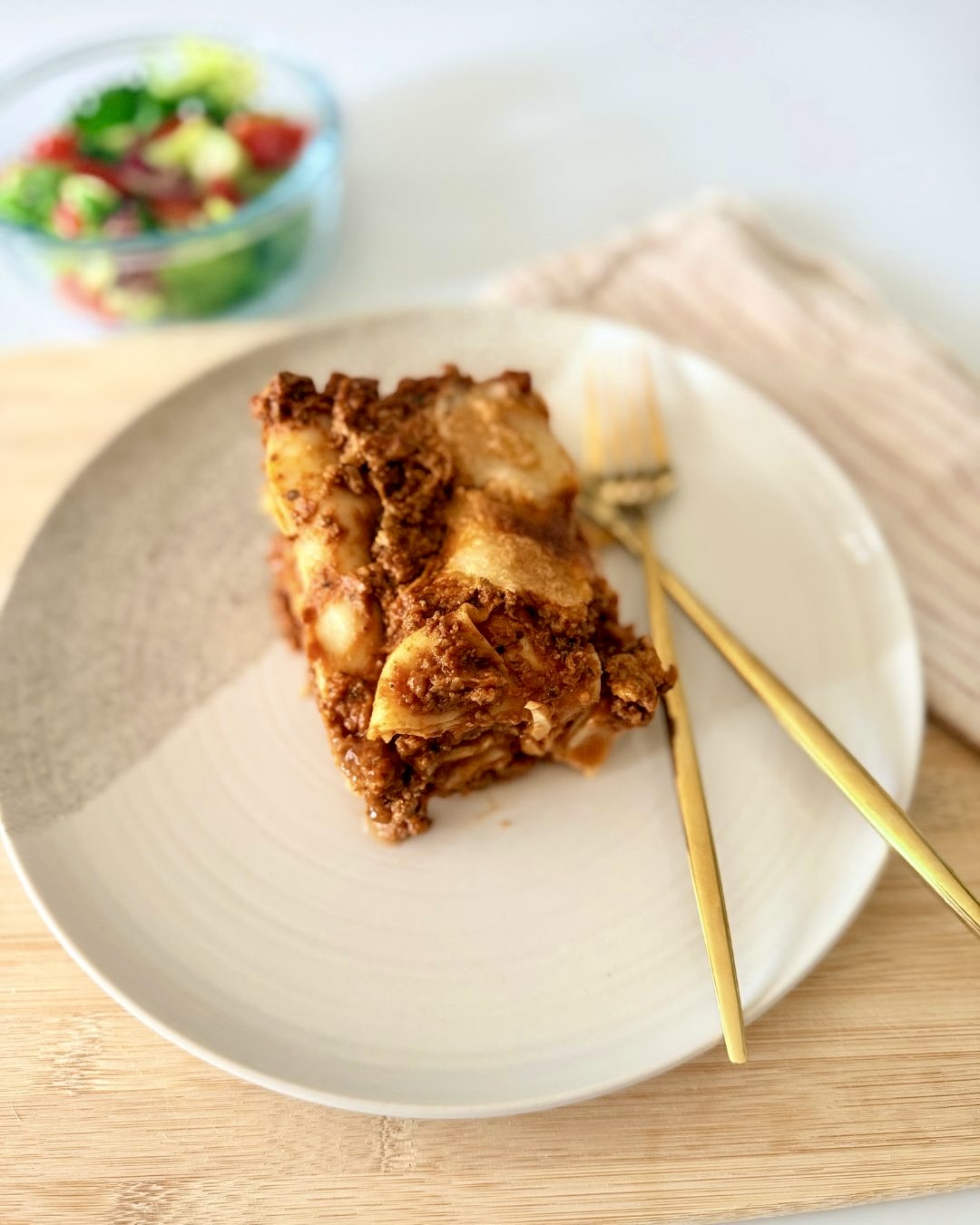 Házi marharagus lasagne olvadt mozzarellával rétegezve, szeletelve, paradicsomos szósszal és zöldséges raguval készítve.