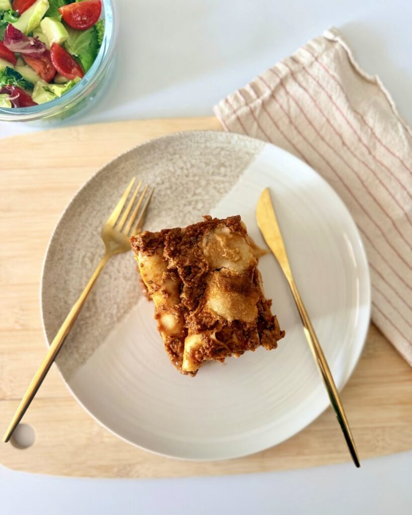 Házi marharagus lasagne olvadt mozzarellával rétegezve, szeletelve, paradicsomos szósszal és zöldséges raguval készítve.