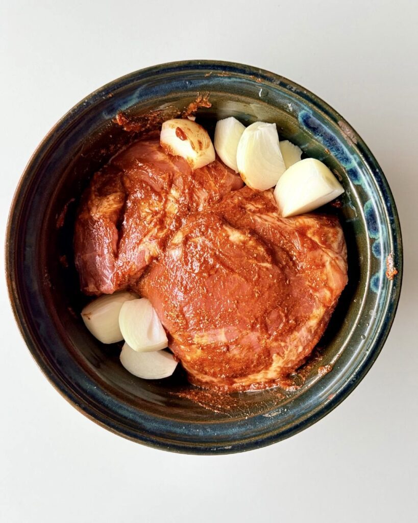 Sütőben sült, szaftos tépett tarja vöröshagymával, szójaszósszal és fűszerekkel, fehér tányéron tálalva