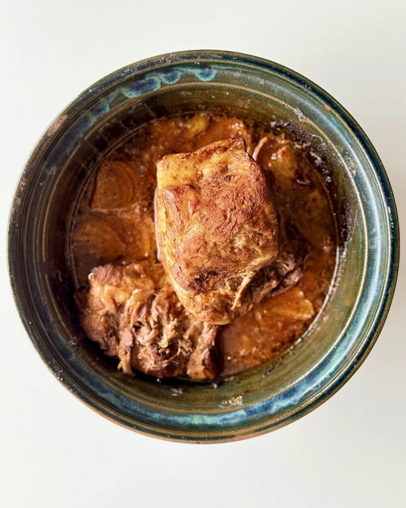 Sütőben sült, szaftos tépett tarja vöröshagymával, szójaszósszal és fűszerekkel, fehér tányéron tálalva