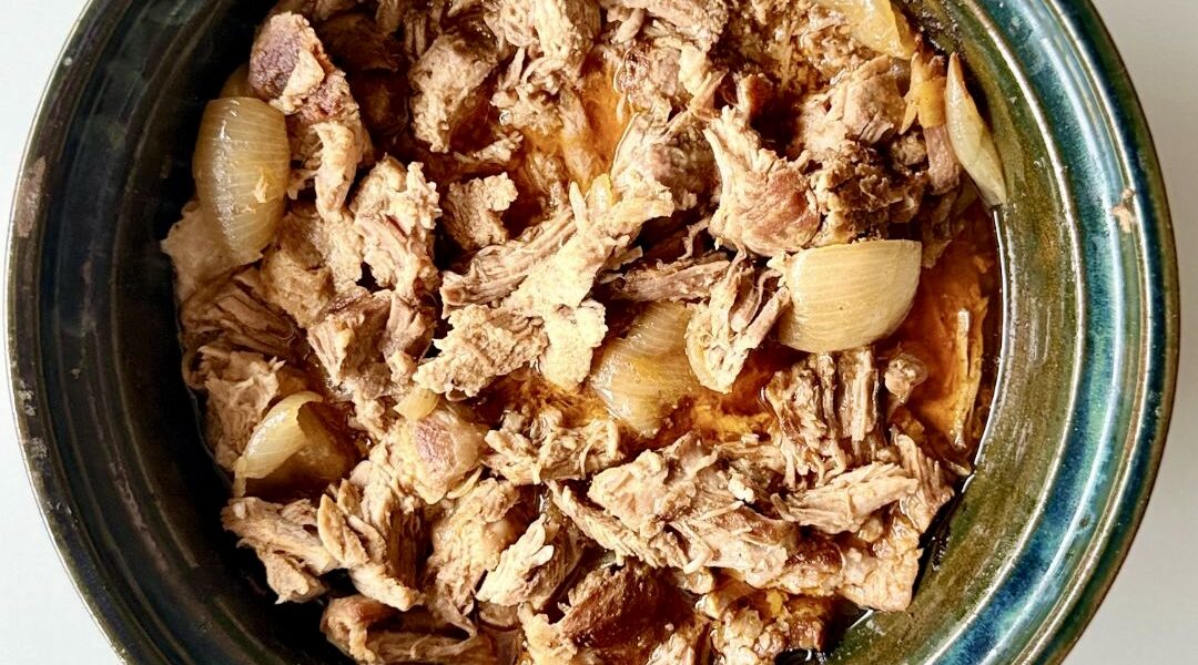 Sütőben sült, szaftos tépett tarja vöröshagymával, szójaszósszal és fűszerekkel, fehér tányéron tálalva