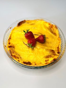 Réteges IR-barát epres-túrós rakott palacsinta szeletelve, tejfölös aranybarna tetőréteggel.