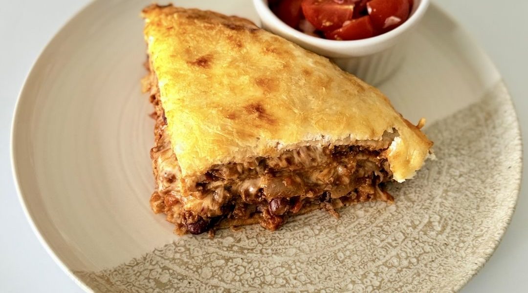 Rétegezett chilis bab torta teljes kiőrlésű tortilla lapokkal, darált marhahússal, vörösbabbal, tejföllel és olvadt sajttal sütve.