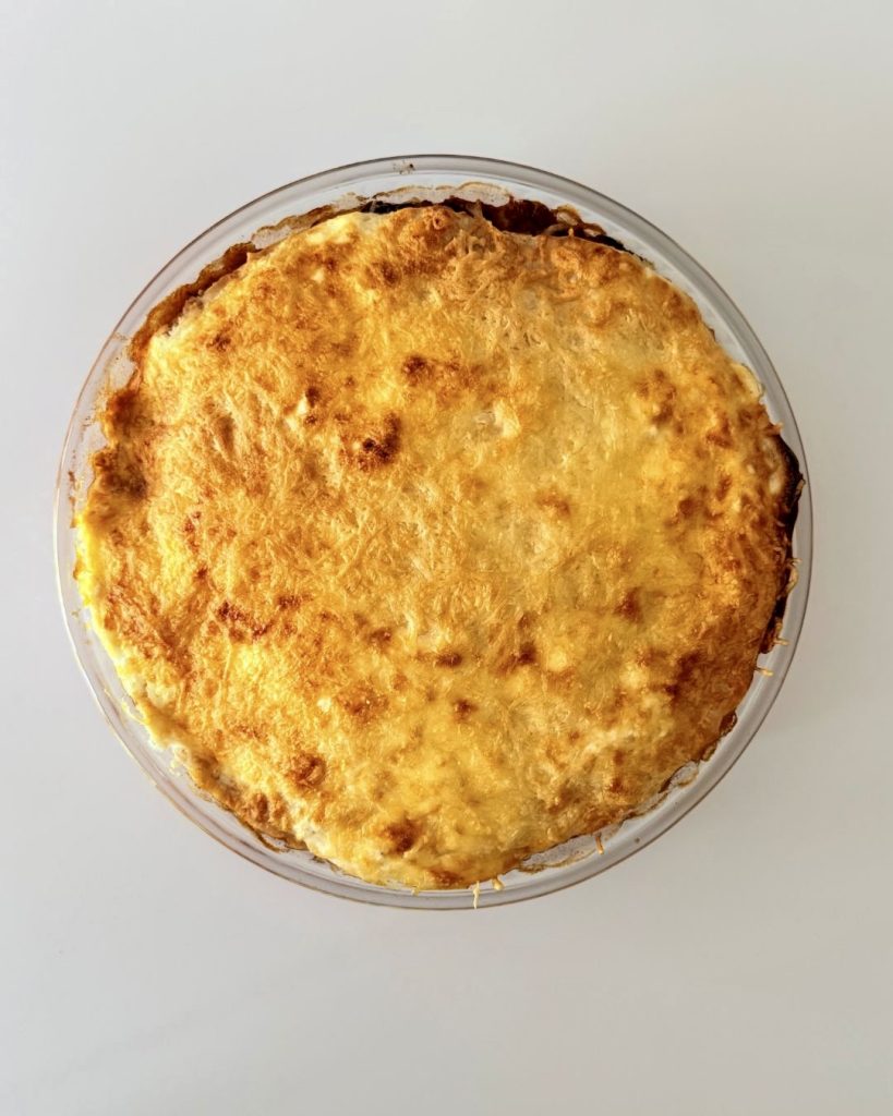 Rétegezett chilis bab torta teljes kiőrlésű tortilla lapokkal, darált marhahússal, vörösbabbal, tejföllel és olvadt sajttal sütve.