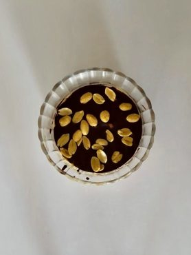 Rétegezett Snickers pohárdesszert görög joghurttal, mogyoróvajjal, étcsokoládéval és mogyoródarabokkal a tetején.