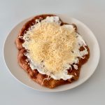 Aranybarnára sült teljes kiőrlésű lángos fokhagymás sajtos-tejfölös feltéttel, kívül ropogós, belül puha állaggal.