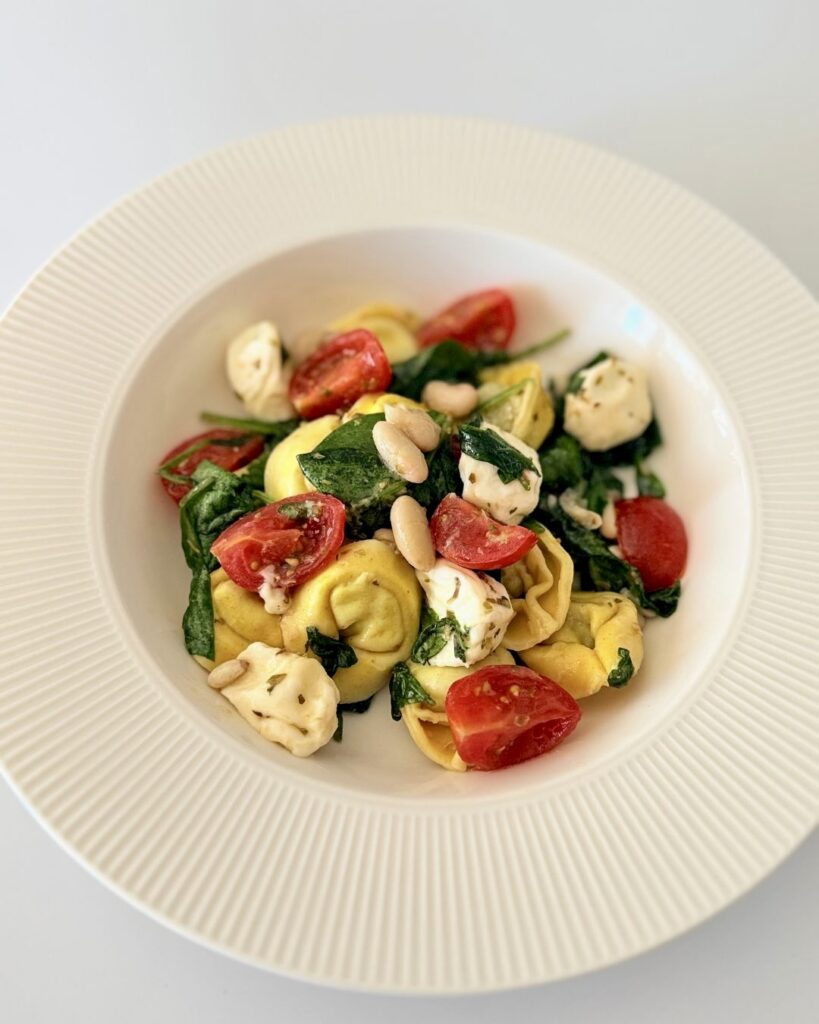 Spenótos-ricottás tortellini saláta bébi spenóttal, mozzarellával, fehérbabbal és koktélparadicsommal.