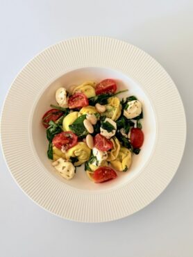 Spenótos-ricottás tortellini saláta bébi spenóttal, mozzarellával, fehérbabbal és koktélparadicsommal.