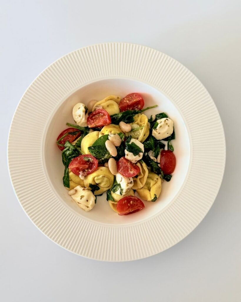 Spenótos-ricottás tortellini saláta bébi spenóttal, mozzarellával, fehérbabbal és koktélparadicsommal.