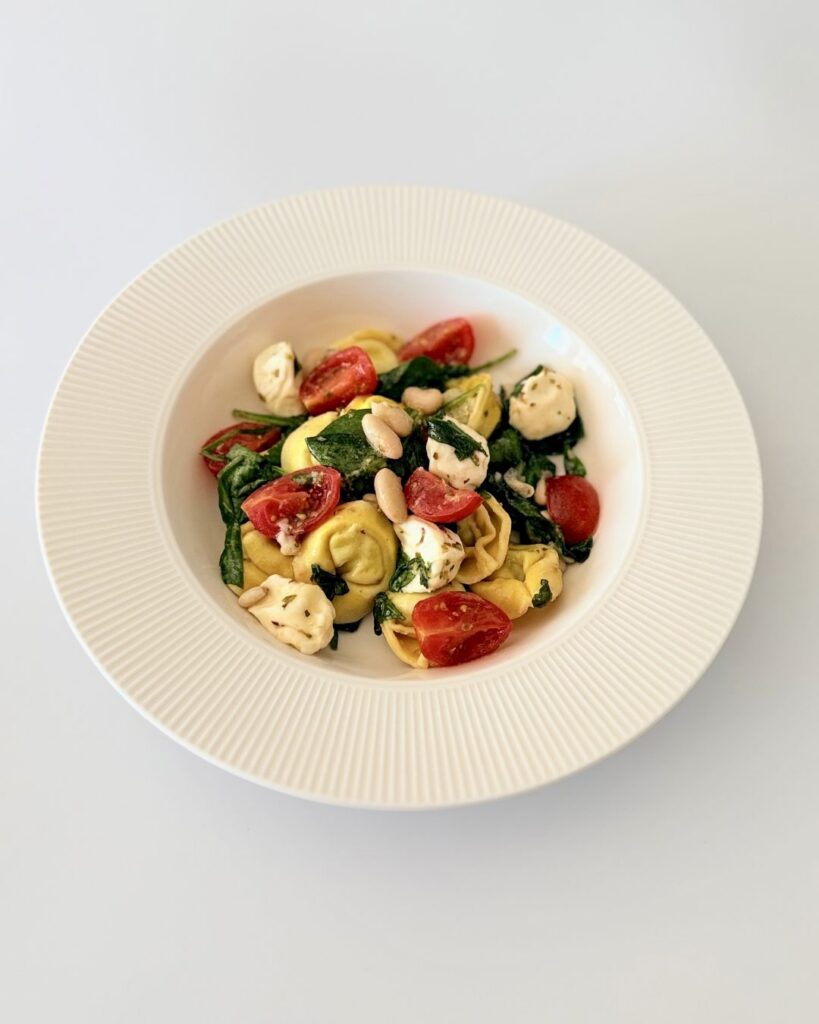Spenótos-ricottás tortellini saláta bébi spenóttal, mozzarellával, fehérbabbal és koktélparadicsommal.