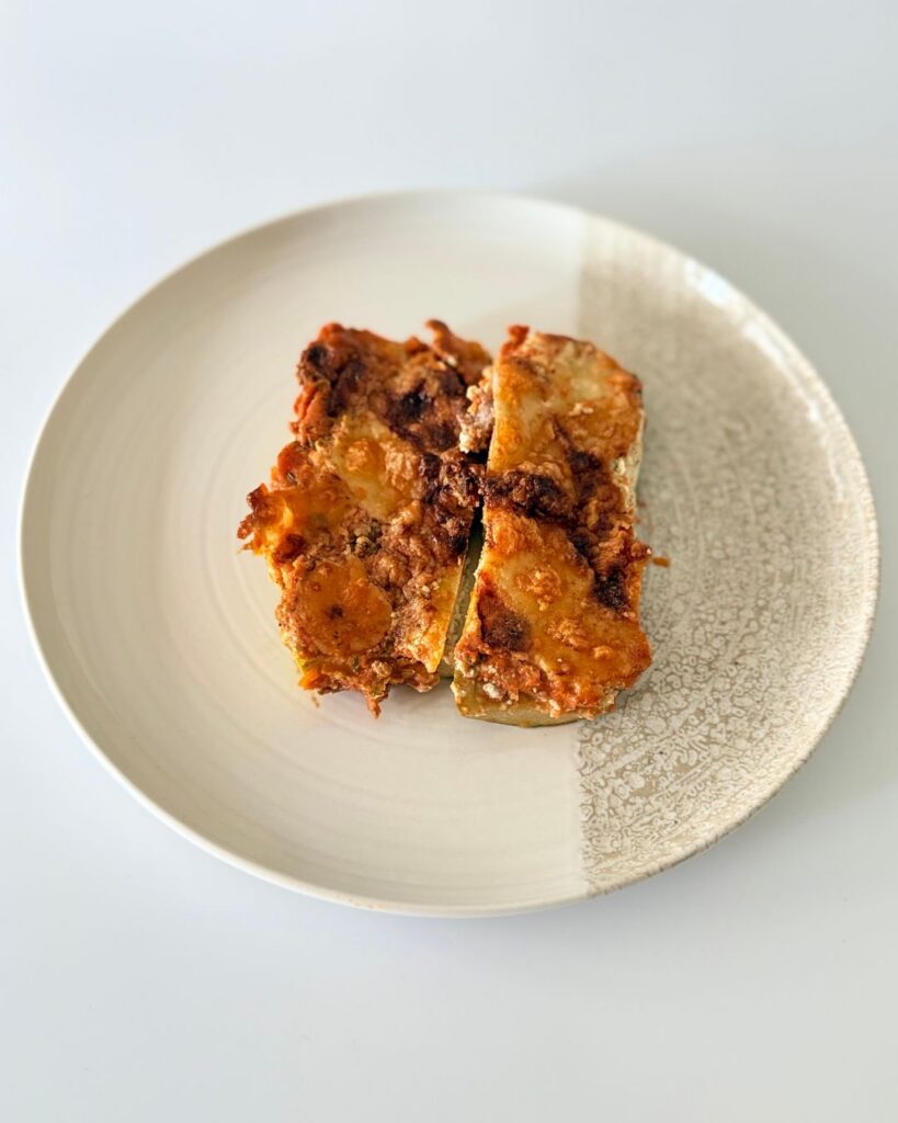 Sajtos-paradicsomos rakott cukkini darált marharaguval, bazsalikomos ricottával és olvadt mozzarellával.