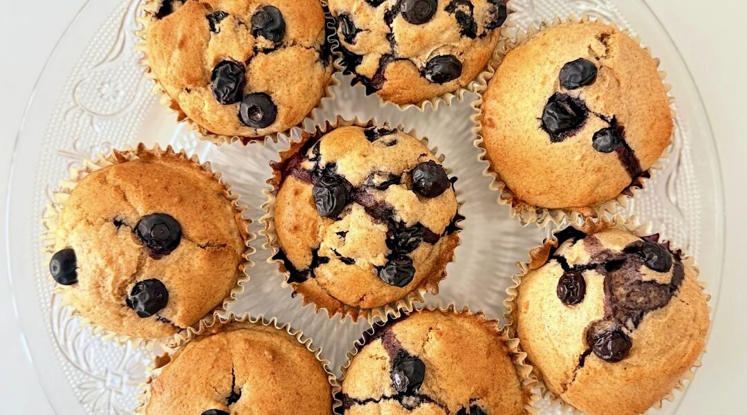 Frissen sült, teljes kiőrlésű lisztből készült áfonyás muffin citromhéjjal, papírkapszliban tálalva.