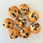 Frissen sült, teljes kiőrlésű lisztből készült áfonyás muffin citromhéjjal, papírkapszliban tálalva.