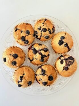Frissen sült, teljes kiőrlésű lisztből készült áfonyás muffin citromhéjjal, papírkapszliban tálalva.