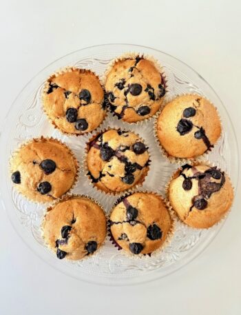 Frissen sült, teljes kiőrlésű lisztből készült áfonyás muffin citromhéjjal, papírkapszliban tálalva.