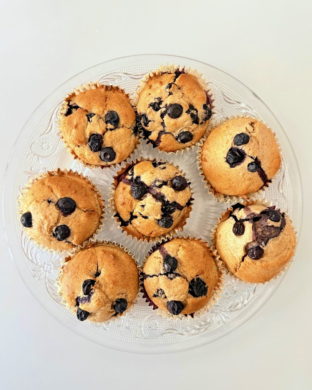 Frissen sült, teljes kiőrlésű lisztből készült áfonyás muffin citromhéjjal, papírkapszliban tálalva.