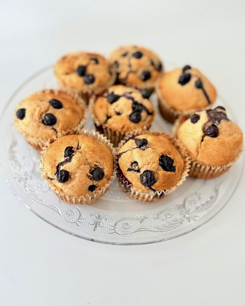 Frissen sült, teljes kiőrlésű lisztből készült áfonyás muffin citromhéjjal, papírkapszliban tálalva.