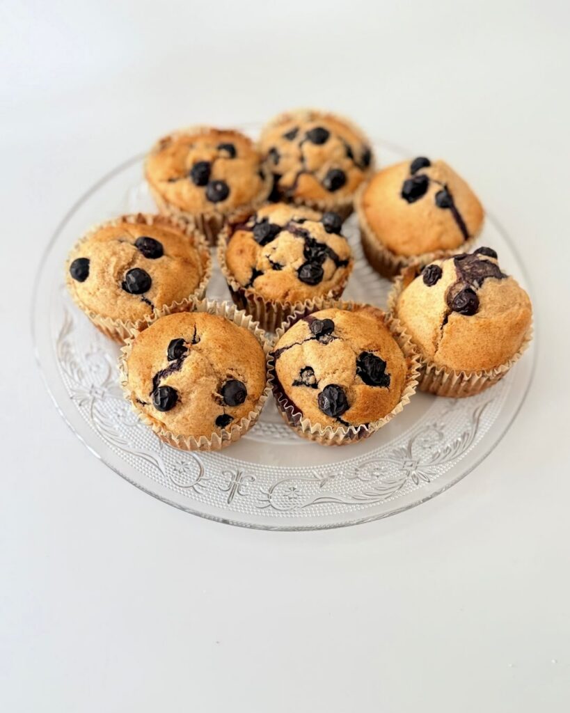 Frissen sült, teljes kiőrlésű lisztből készült áfonyás muffin citromhéjjal, papírkapszliban tálalva.