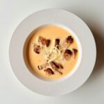 Krémes chilis sajtkrémleves pirított teljes kiőrlésű kenyérkockákkal és reszelt sajttal tálalva.