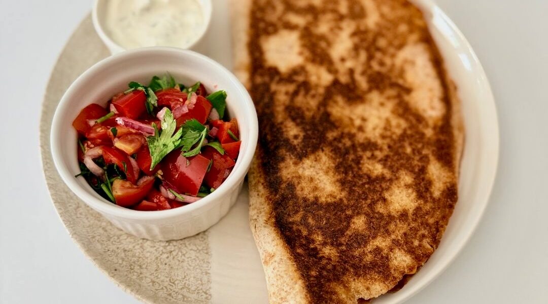 Ropogósra sült teljes kiőrlésű csirkés quesadilla fekete babbal, kukoricával és olvadt gouda sajttal, friss pico de gallóval tálalva.