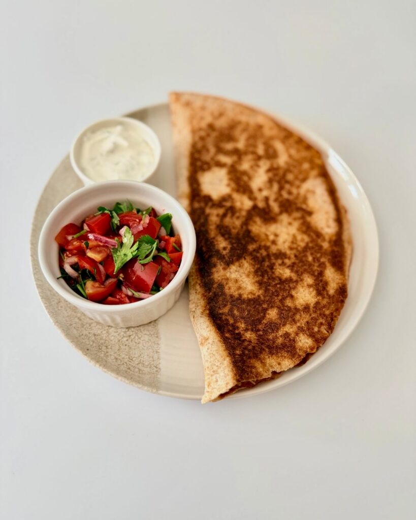 Ropogósra sült teljes kiőrlésű csirkés quesadilla fekete babbal, kukoricával és olvadt gouda sajttal, friss pico de gallóval tálalva.
