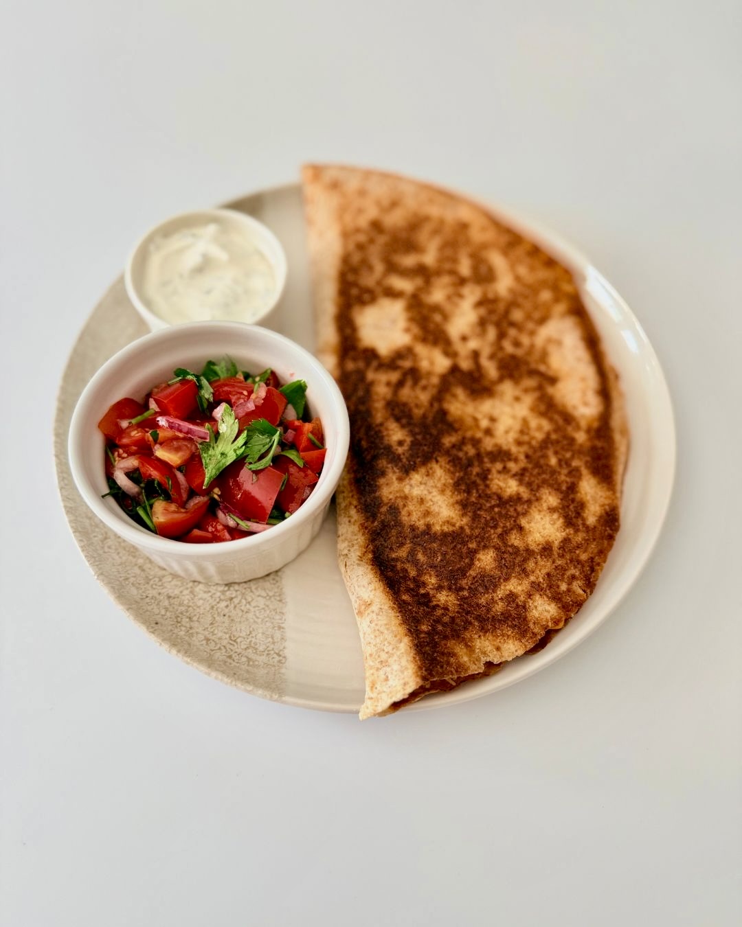 Ropogósra sült teljes kiőrlésű csirkés quesadilla fekete babbal, kukoricával és olvadt gouda sajttal, friss pico de gallóval tálalva.